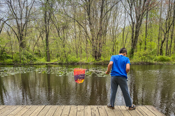 Boy preparing to catch fish with net in pond.
