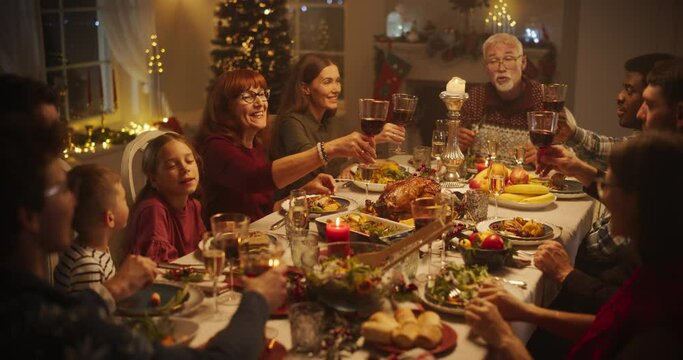 Parents, Children and Friends Spend Christmas Dinner Together at Home. Multicultural Family Raising Wine Glasses and Toasting, Celebrating a Holiday with a Delicious Turkey Meal - Powered by Adobe
