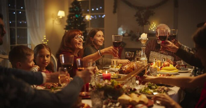 Christmas Celebration at Home with Multicultural Group of Loved Ones Enjoying a Turkey Dinner. Festive Atmosphere Fills the Room while Family Raising Glasses, Toasting, Celebrating Winter Holiday