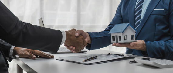 Shaking hands of customers and salespeople after agreeing a successful home loan contract for buying or selling a new home.