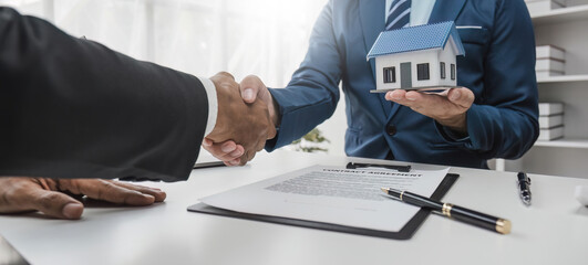Shaking hands of customers and salespeople after agreeing a successful home loan contract for...
