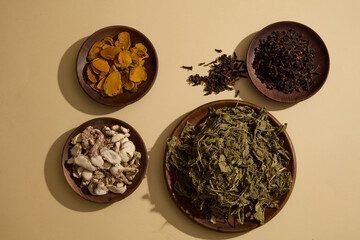 Aromatic Ginger, Dried turmeric, Cloves and Dried mint leaves are decorated on round wooden dishes over beige background. Healthy medicine concept