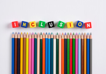 Inclusion concept in education and schooling. The word inclusion on colorful cubes with crayons.
