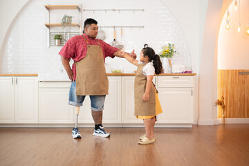 A plus size family with a father wearing a prosthetic leg, The daughter had fun playing with her father before helping cook. in the kitchen room of the house.