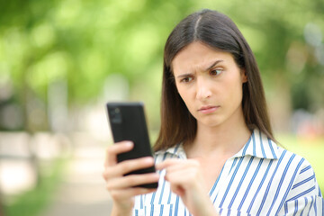 Woman reading suspicious message on phone - obrazy, fototapety, plakaty