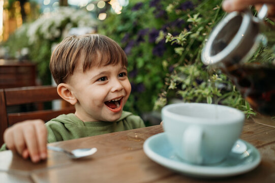 Happy boy with mother pouring tea in cup