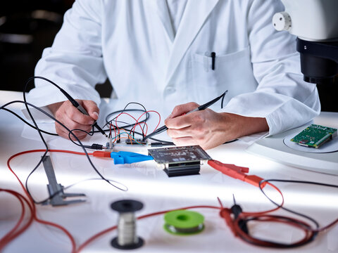 Hands of scientist working on circuit board with tools