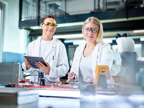 Smiling young scientists working in electronics laboratory