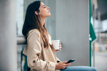 Young woman wearing wireless in-ear headphones listening to music