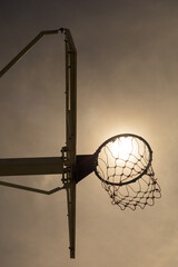 Outdoor basketball hoop against warm sky.Low angle view.