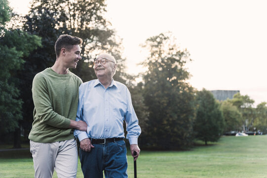 Young man assisting his grandfather walking in a park