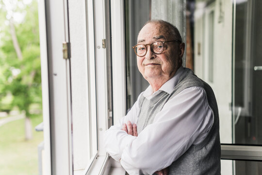 Portrait of senior man standing at open window