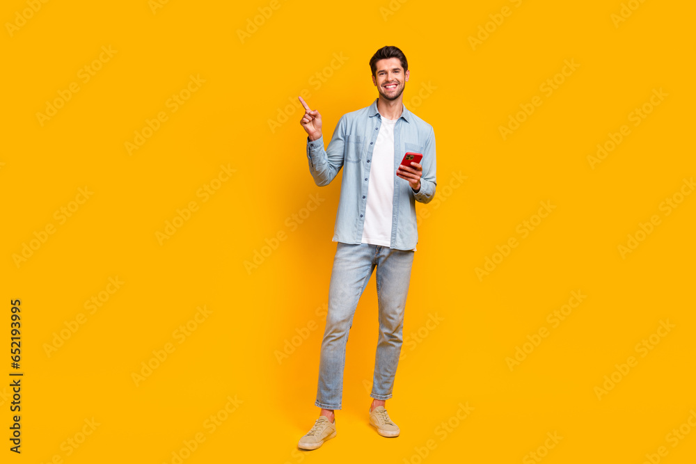 Poster photo of millennial guy browsing web smart gadget pointing finger empty space ads isolated vivid col