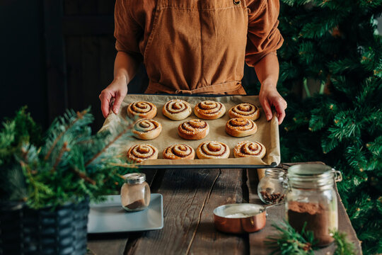 Woman holding cinnamon buns in tray at home