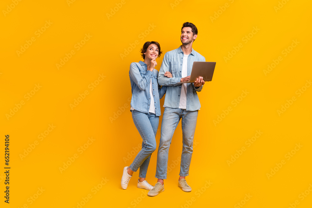 Poster full length photo of minded friends wear denim stylish clothes use netbook look up empty space offer