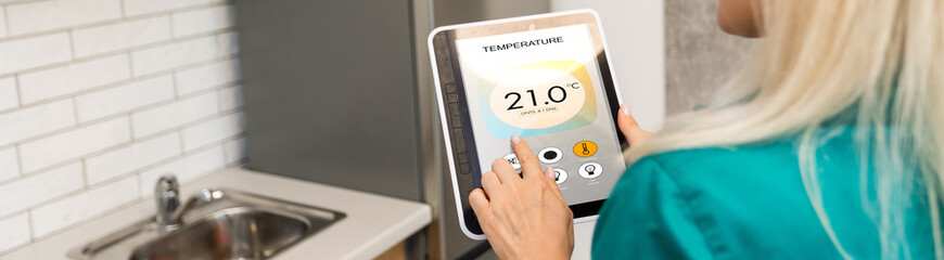 Rear view of young woman making setting of her home with online smart home application