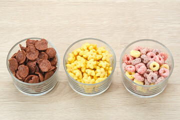 Various Cereal for breakfast on glass bowl, chocolate flakes, colorful flakes, and honey star.

