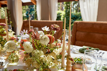 Graceful setup of chambers table, featuring a tasteful interplay of candles and artfully arranged flowers cast in shadows.Wedding imbued with the elegance of Provence.