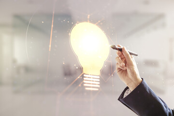 Man hand with pen draws virtual Idea concept with light bulb illustration on blurred office...
