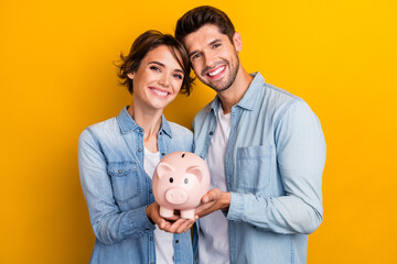 Photo of positive lovely couple hold pink piggy box save money for future wedding isolated shine...