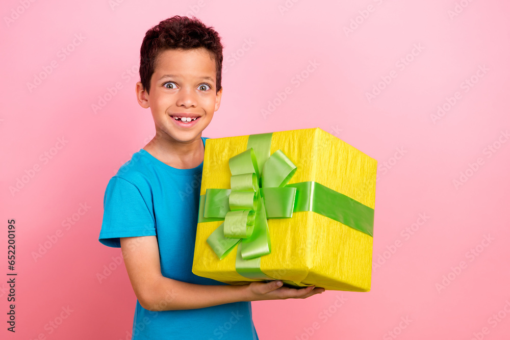 Sticker photo of cute excited little boy dressed blue t-shirt rising big present box isolated pink color bac