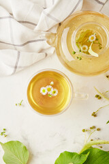 Tea ceremony, cup and teapot of freshly brewed herbal natural tea. Linden and chamomile healthy beverage. Cozy home concept