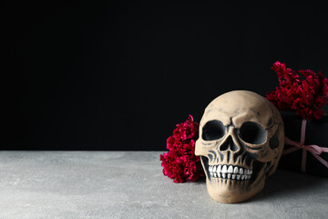 Skull and flowers on black background, space for text