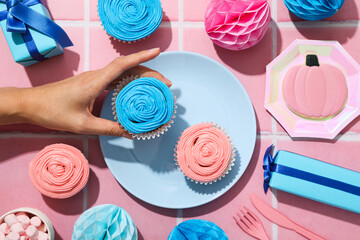 Gift boxes, cupcakes and female hand on pink background, top view