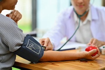 Doctor measuring arterial blood pressure of elderly lady in hospital. Elderly healthcare and...