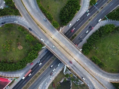 Aerial drone multilevel junction overpass highway with grass gardens at rush hour with moderate traffic america