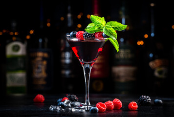Wild berries - black cocktail drink with vodka, sugar syrup, lemon juice, blueberries, raspberries,...