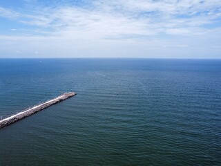 mezmerizing aerial drone shot of the sea and sky at daytime with a dock at the side in america