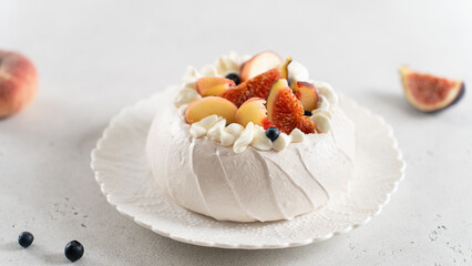 Pavlova cake with peach, figs, blueberries and vanilla cream on a white background. Close up....