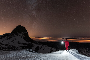 Night landscape with Santa Claus holding lantern in snowy mountains during Christmas time