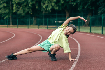 Child training at school physical lesson, teenage girl stretching outdoors.