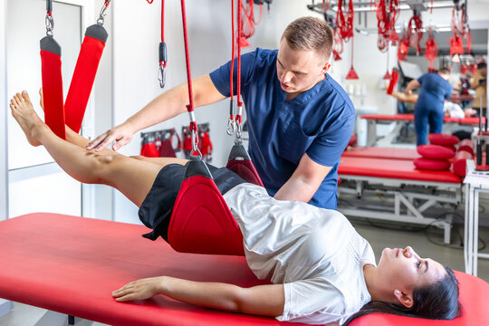 Rehabilitation specialist doing treatment on suspension straps to patient.