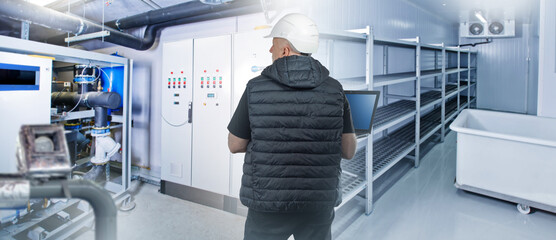 Engineer inside cold storage warehouse. Man inspects industrial refrigerator. Freezing equipment....