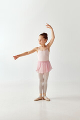 Portrait of small adorable preschool ballerina dancer girl in rose tutu ballet dress white legging standing posing hold hands up on white background. © Lustre Art Group 
