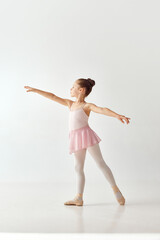 Portrait of small adorable preschool ballerina dancer girl in rose tutu ballet dress white legging...