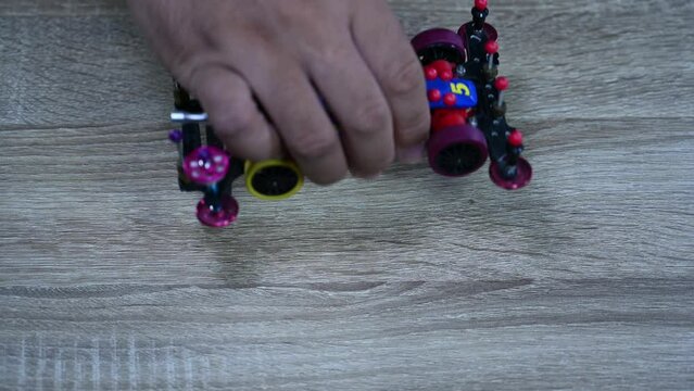 Checking the wheels of a Tamiya Mini sports car by dropping it on a table inside a shop in Bangkok, Thailand