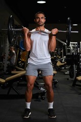 Strong Hispanic man doing barbell curl for biceps strength at a gym. - obrazy, fototapety, plakaty