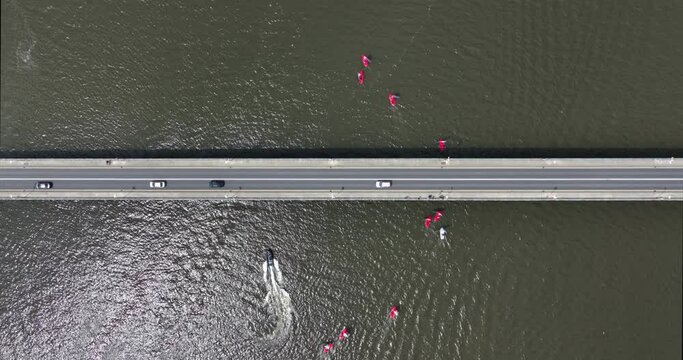 Sailboats compete in a summer race by sailing under a road bridge 4k