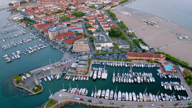 4k drone flying over footage (Ultra High Definition) of Grado port, small town located between Venice and Trieste. Nice evening seascape of Adriatic sea witj public beach. Vacation concept background.