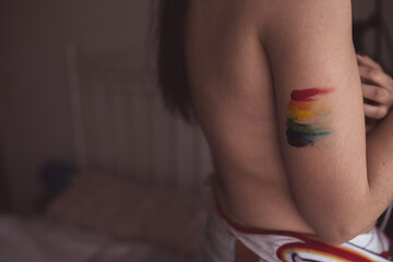 Attractive naked woman covering breast and drawing LGBT symbol