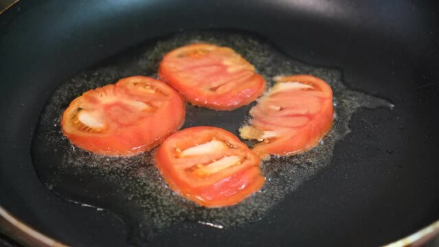 Cooking pan with oil and slices of tomatoes, preparing healthy breakfast of shakshuka