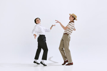 Beautiful young woman and man in stylish retro clothes dancing lindy hop isolated on white studio...