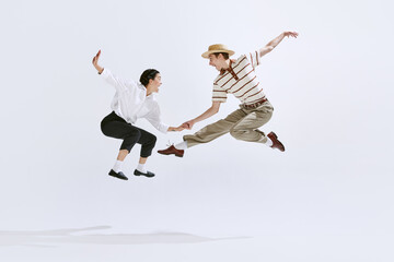 Happy, attractive young man and woman in stylish vintage clothes dancing lindy hop isolated on...