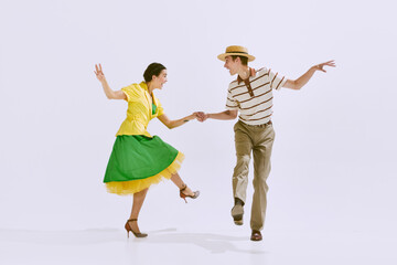 Attractive, positive young couple, man and woman in stylish clothes dancing isolated on white studio background. Concept of art, hobby, retro dance, vintage style, choreography, beauty. Ad