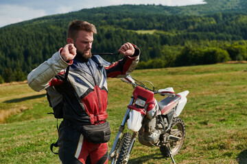 A professional motocross rider, clad in a full suit, gloves, and backpack, prepares for a daring...