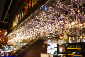 Fototapeta na wymiar Glasses hanging in the bar. Night bar drinks in huge city. Pub at night in big city. 